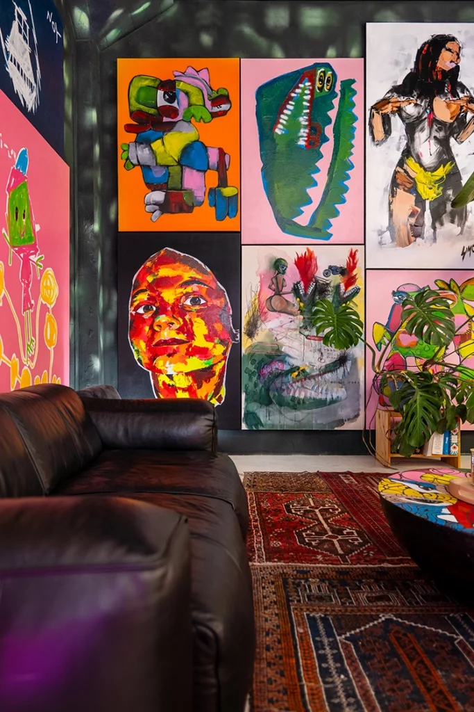 black-leather-sofa-art-gallery-style Cozy lounge corner with a black leather sofa against a colorful wall of contemporary art in Rotterdam.