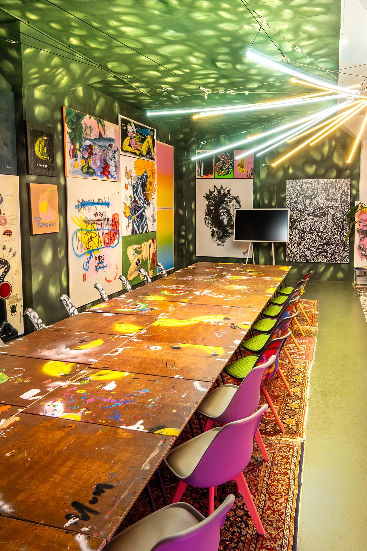 Creatieve vergaderruimte in Rotterdam met lange beschilderde tafel, originele kunstwerken en designstoelen in het atelier van Dutch Art Room.